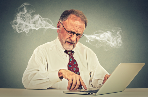 Stressed elderly old man using computer blowing steam from ears